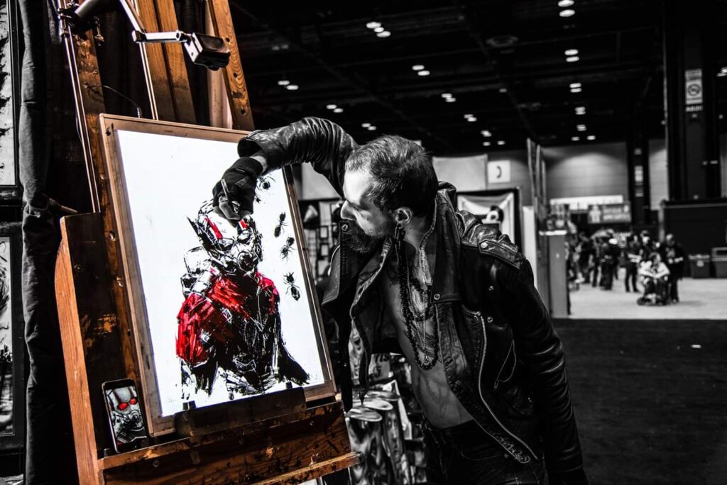 comic con artist drawing marvel hero ant-man on a white canvas