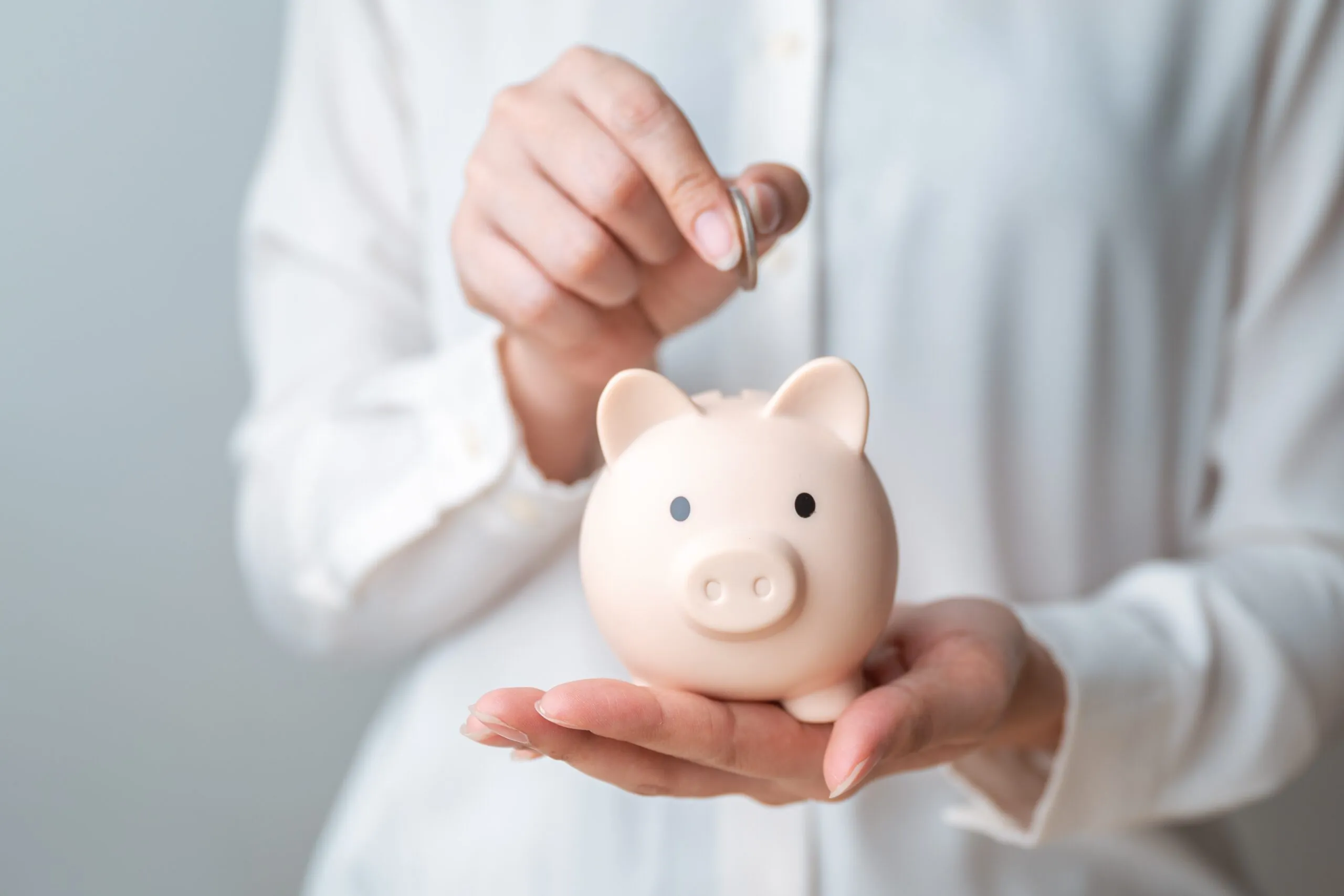 close up of person putting coin into a piggy bank