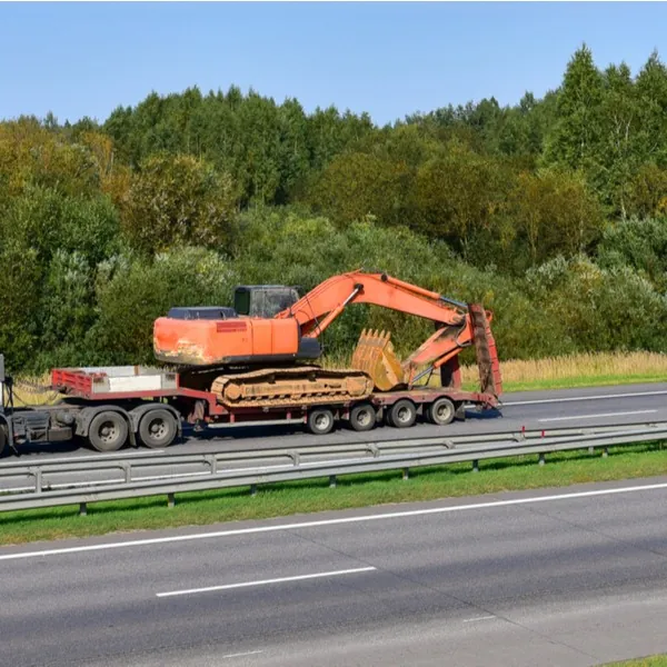 A large excavator being transported on a lowboy trailer