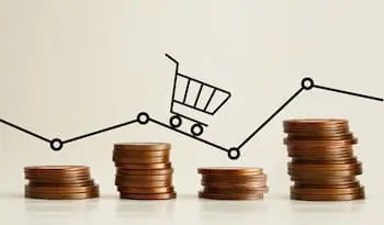 small pile of coins lined up asymmetrically under a drawing of a shopping cart rolling along fluctuating graph