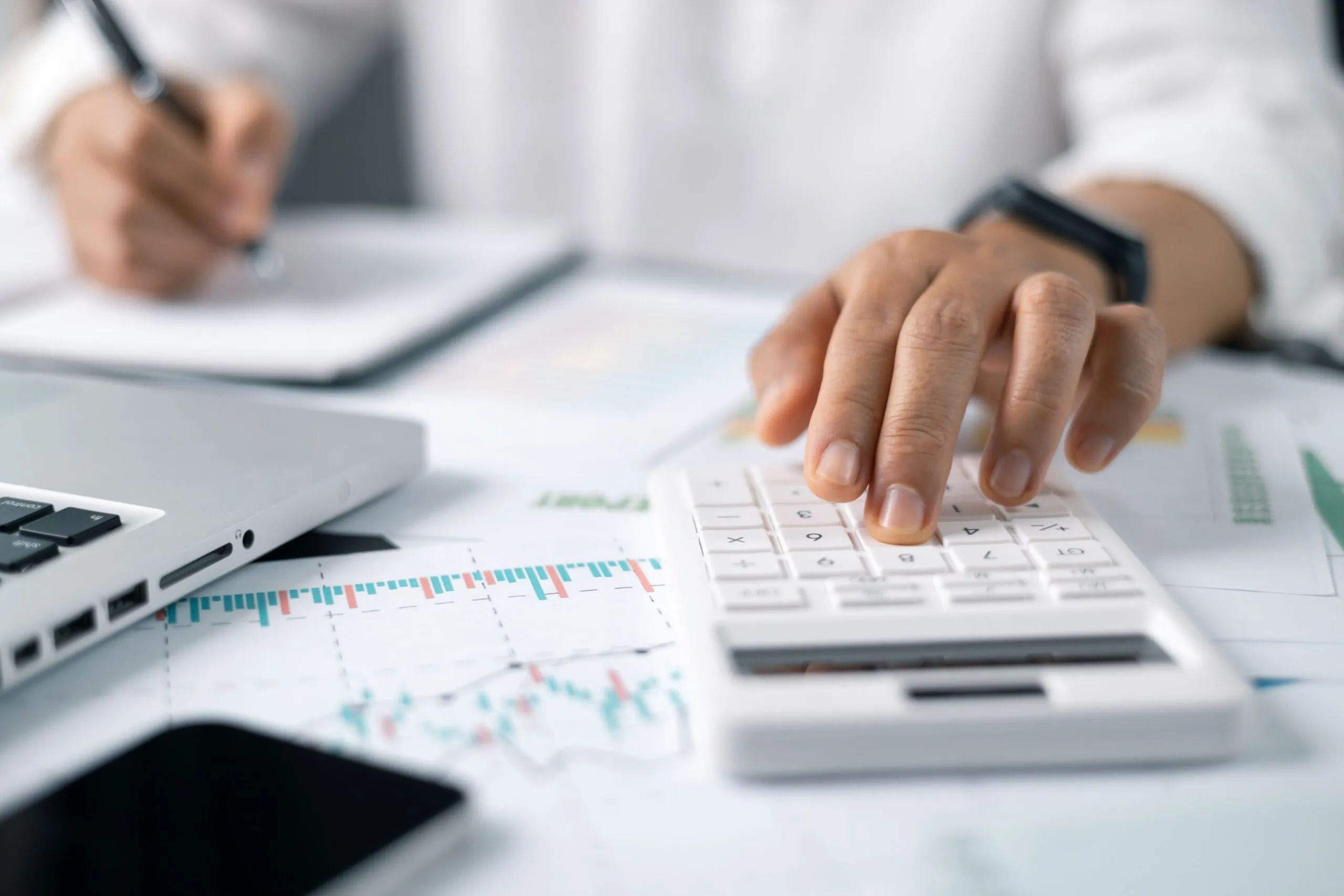 hand typing on calculator over financial papers