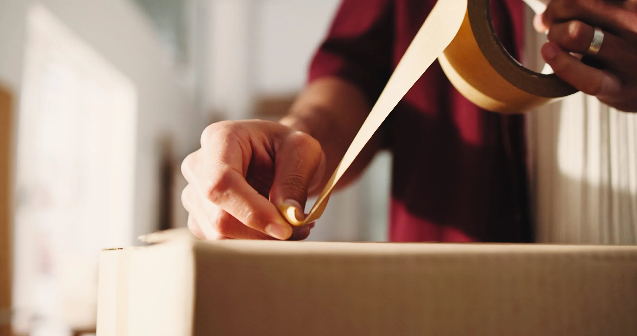 man taping cardboard box closed closeup, small business shipping