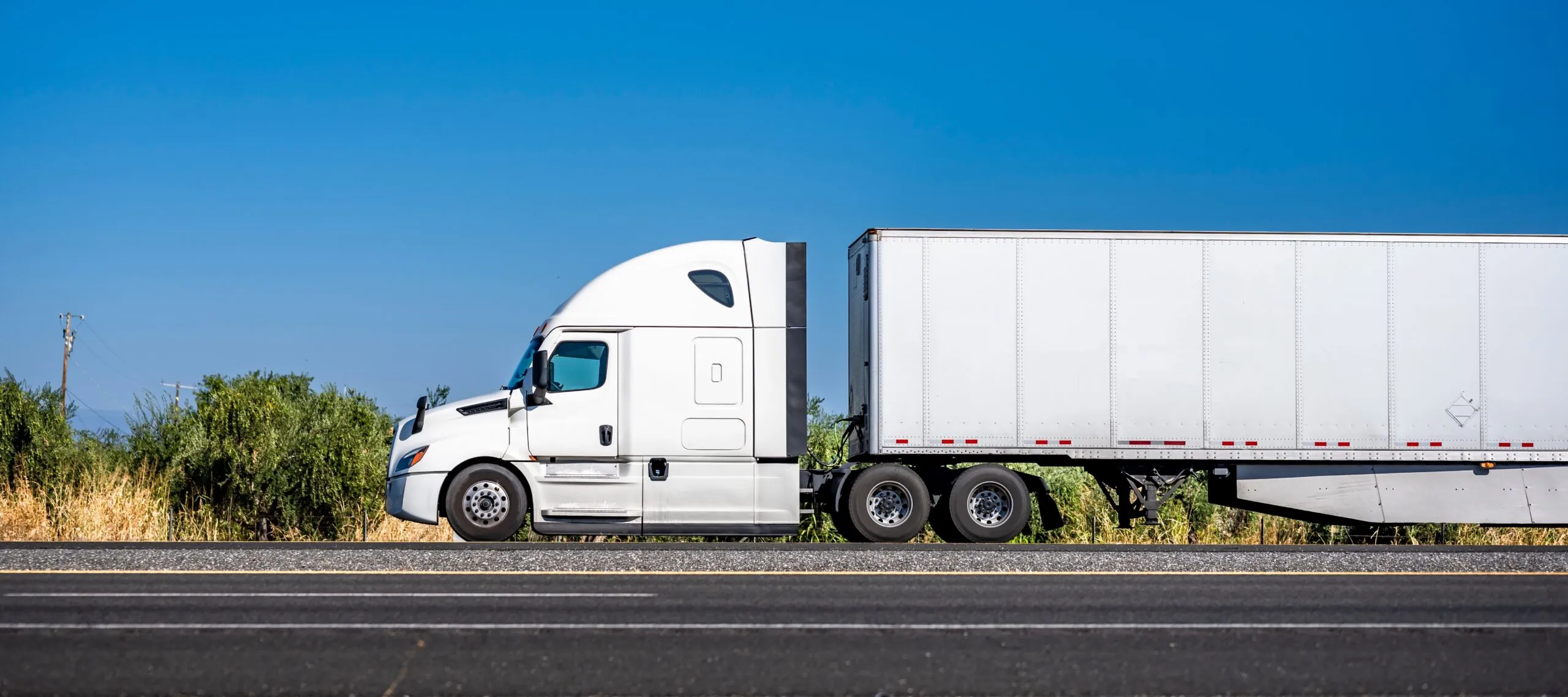 white semi truck driving on road side view