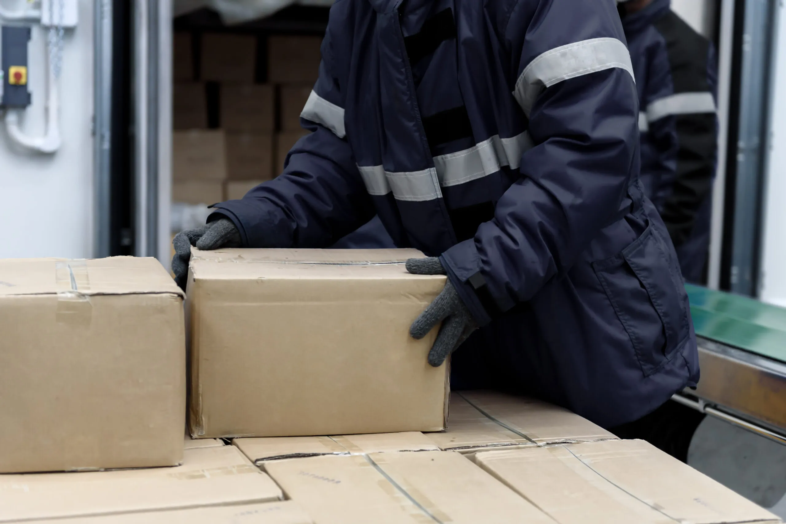 worker placing cardboard box on other boxes