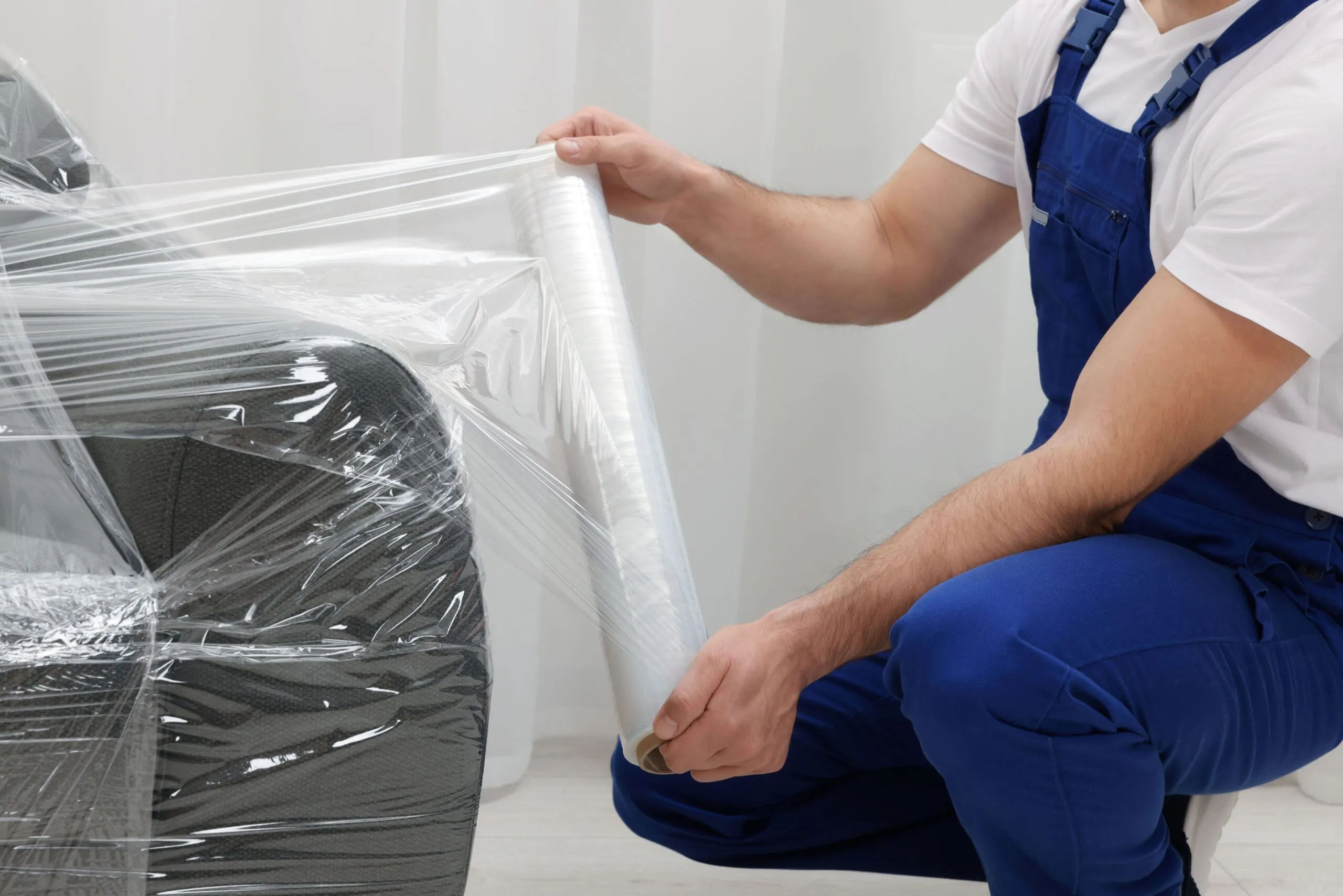 worker wrapping sofa with stretch film, furniture packing