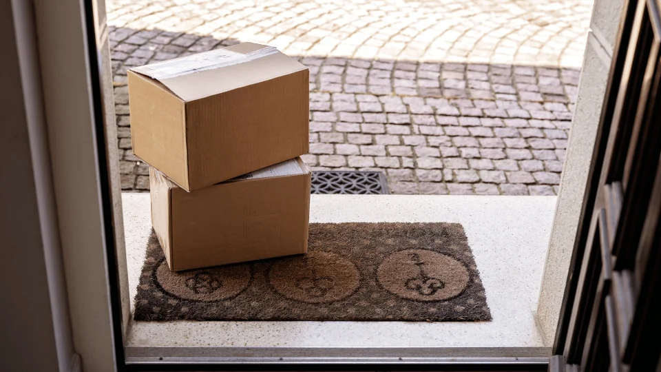 Differences Between LTL and a Parcel cardboard boxes stacked on a welcome mat in front of door
