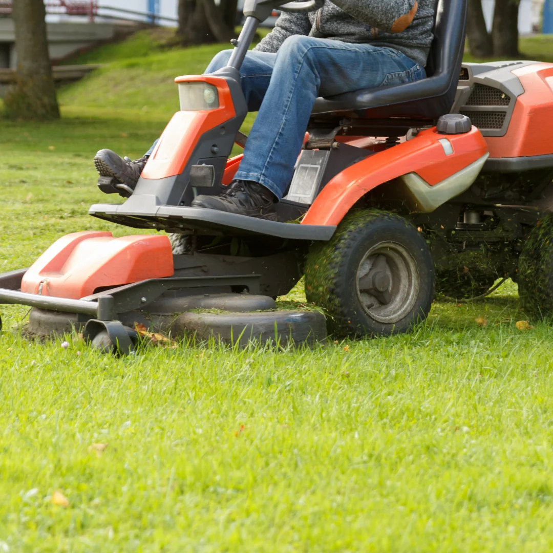 a man on a red riding lawn mowers