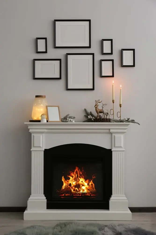 modern white stylish interior fireplace and mantel with pictures hanging above it