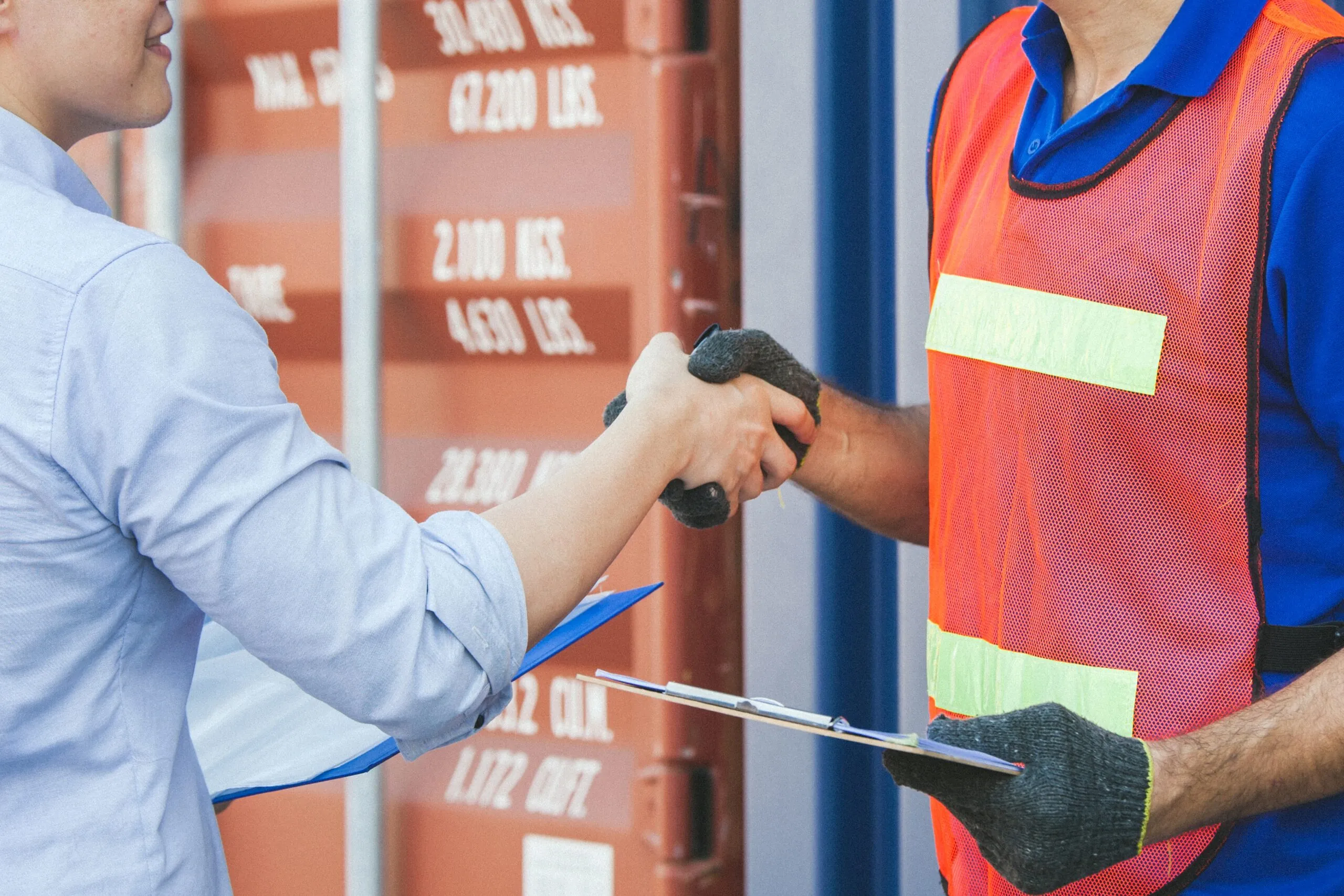 workers shaking hands near freight container
