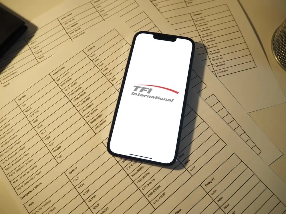 TFI International logo on a iPhone and the phone sits on international invoices