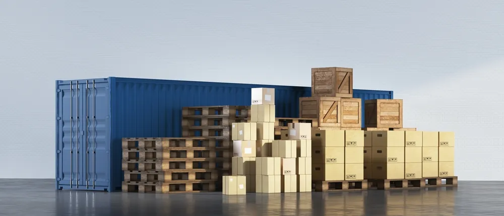 pallets, boxes, and crates sitting next to a blue shipping container 