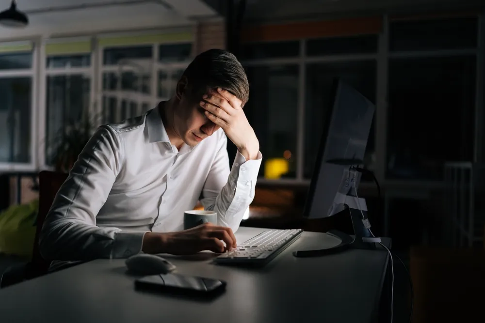 Is Your Freight Shipping Strategy Costing You Customers man looking frustrated at computer in dark office