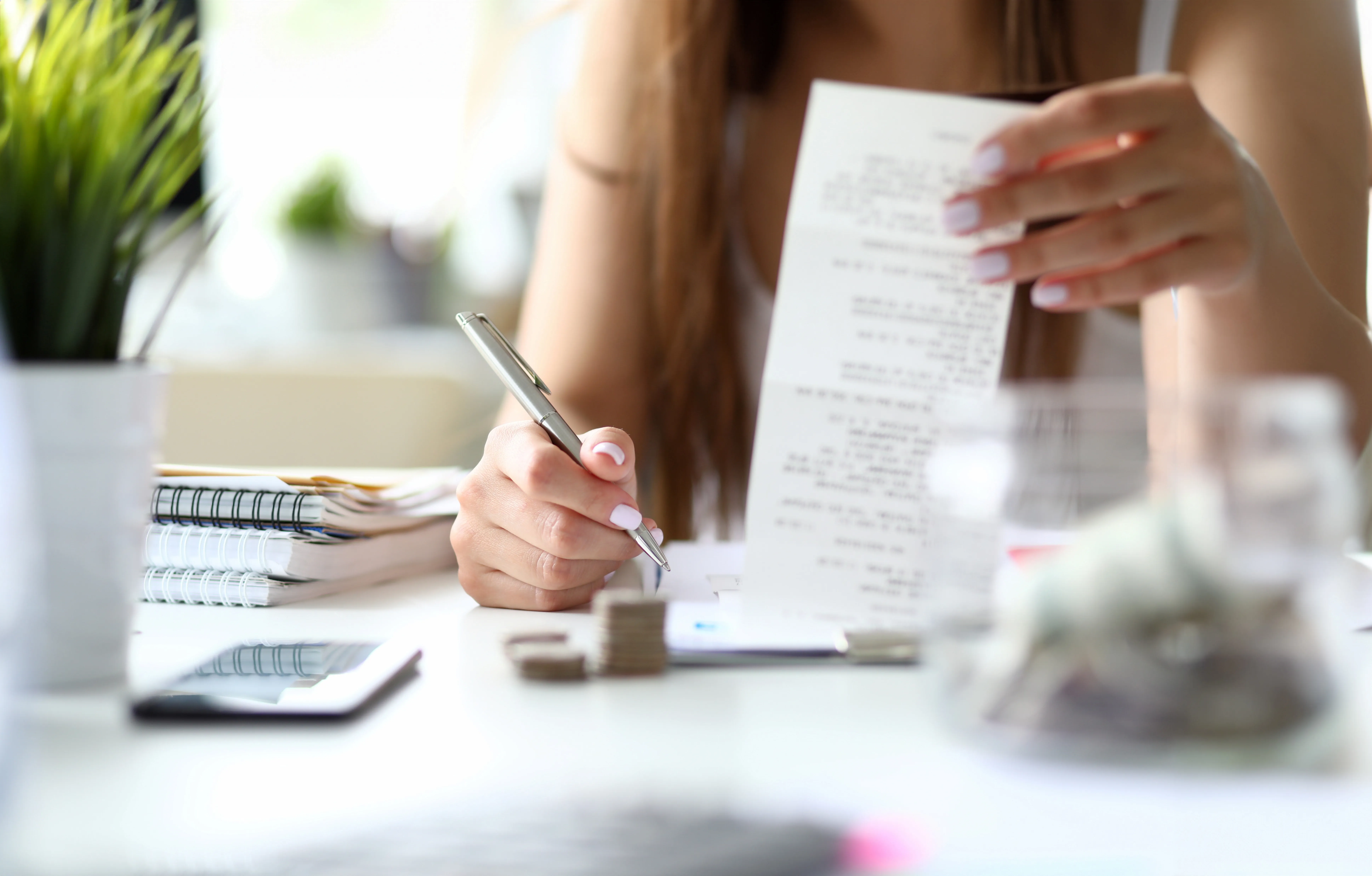 woman looking at receipt and budgeting at desk