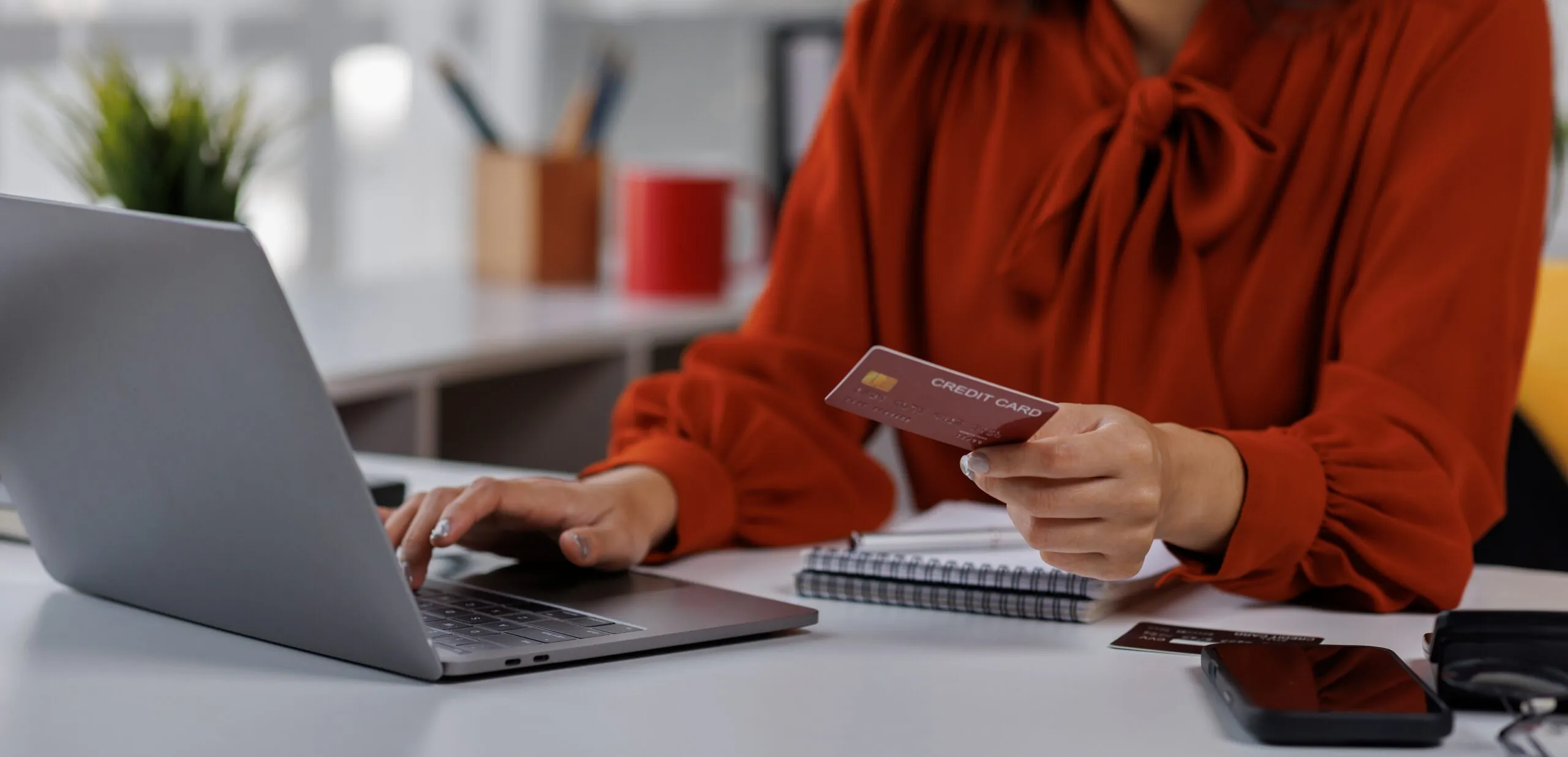 woman on computer at desk holding credit card