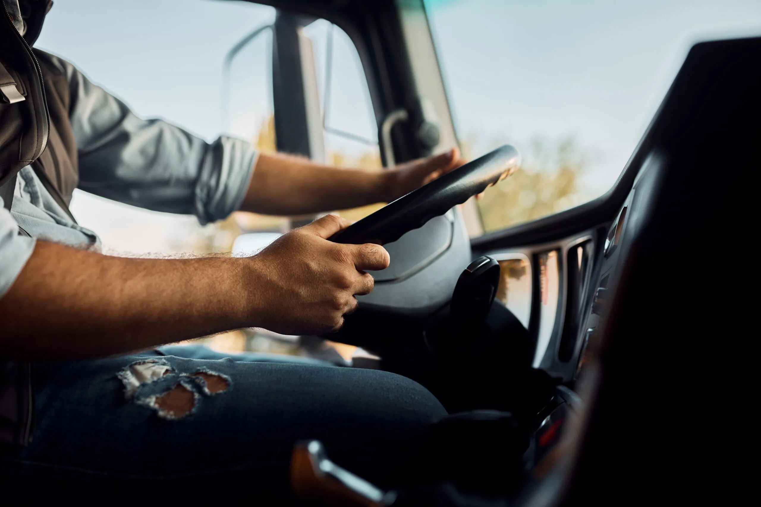close up of truck driver driving behind wheel