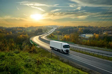 white truck driving on the highway through forested landscape