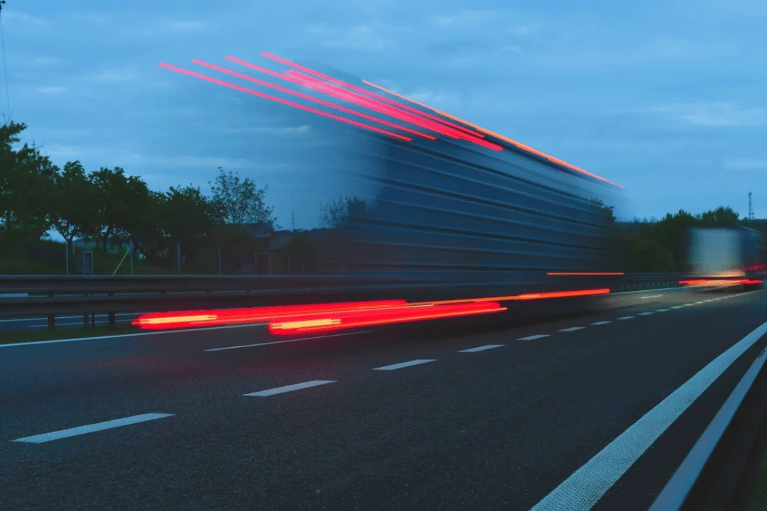 Five Reasons to Use Expedited Freight Shipping truck speeding down highway in the evening
