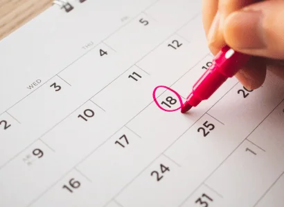 female circling date on calendar with pink marker