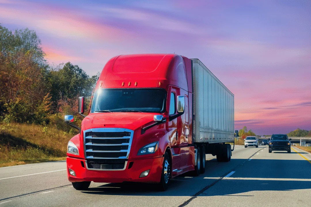 red semi trailer driving down Tennessee highway at sunset