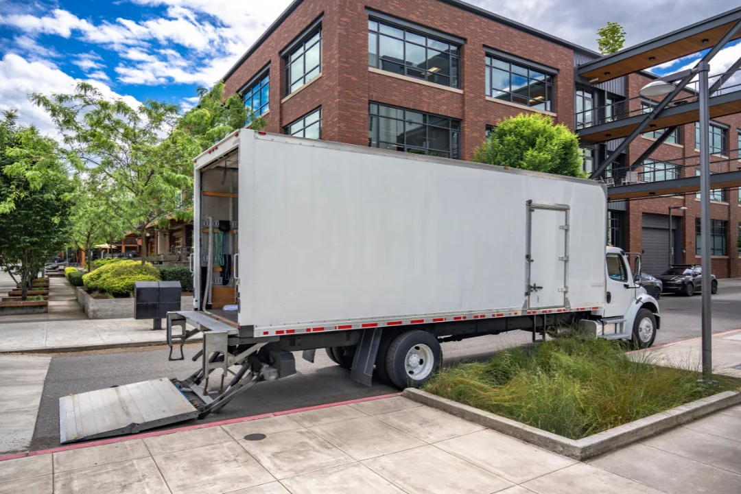 Special Requirements When Shipping Freight small delivery truck with lift gate in front of an apartment complex on a city street