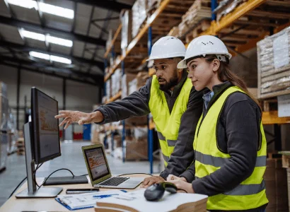 two logistics warehouse workers analyzing data on computer