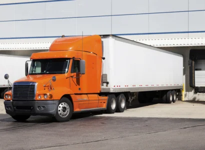 orange semi truck backed up to a loading dock