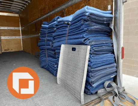 bundled moving blankets inside of truck with lift gate leaning on them