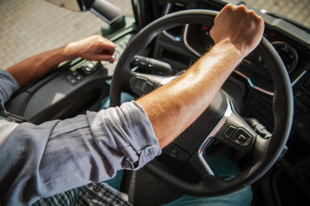 overhead view of a truck driver with arm on a steering wheel 