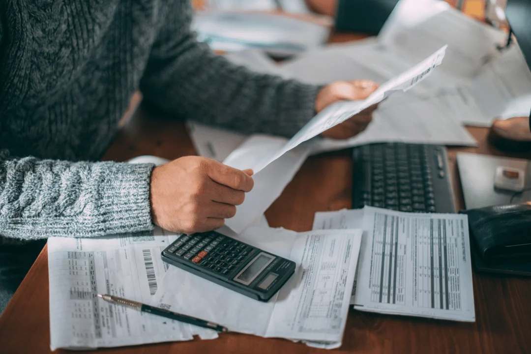 What Trends Will Shape Holiday Shipping person reading over bills in front of computer with calculator next to them