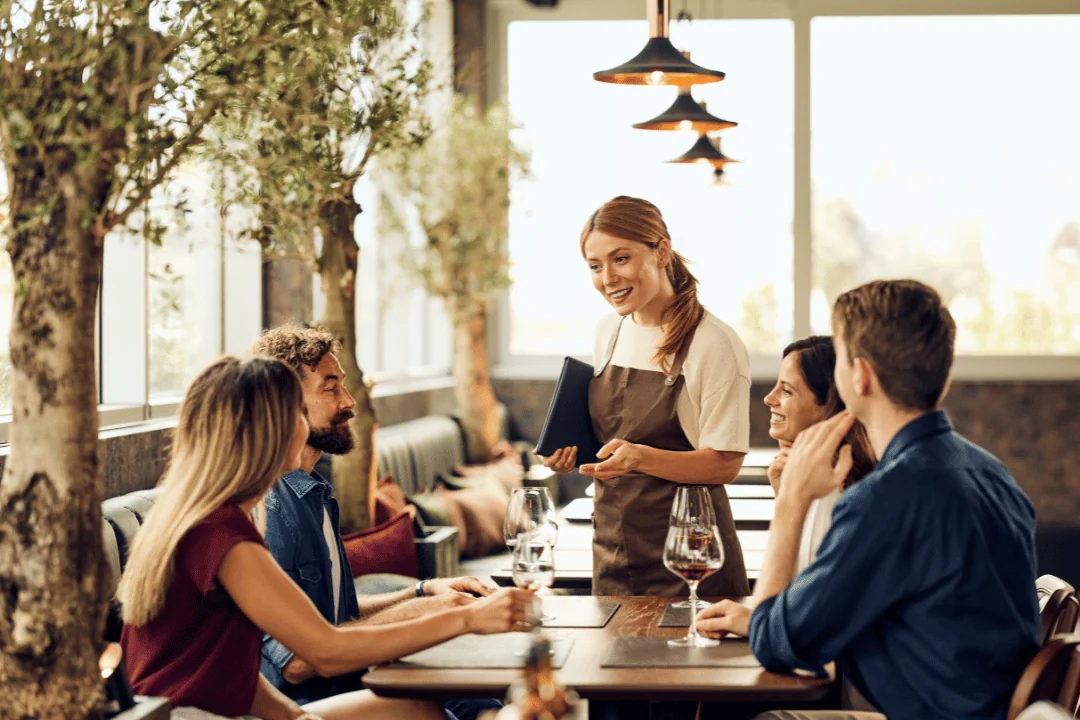 Freight Shipping for Fine Dining Restaurants a hostess at a relaxed fine dining restaurant talking to a party at four seated at a table with wind glasses for each person