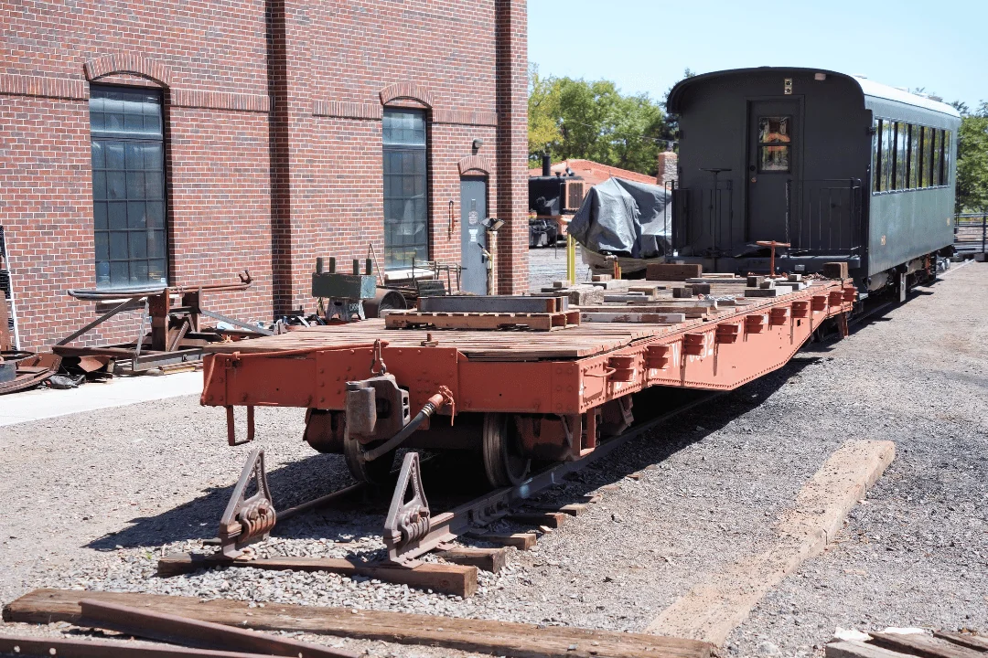 Freight Shipping Circuses an old railroad flatcar coupled to a passenger car on a stub track
