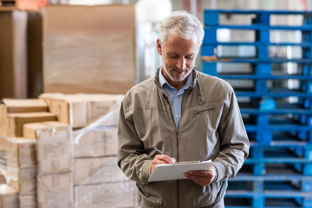 freight worker with clipboard and pallets