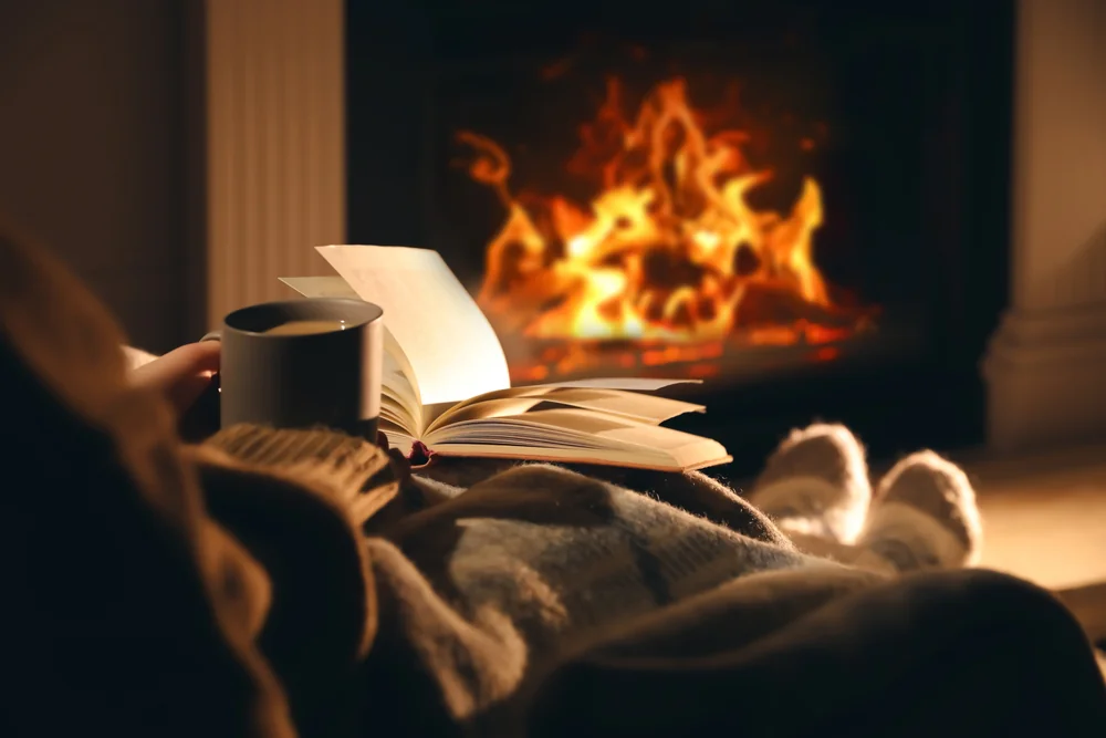 The Quiet Season ALT person reading near fireplace