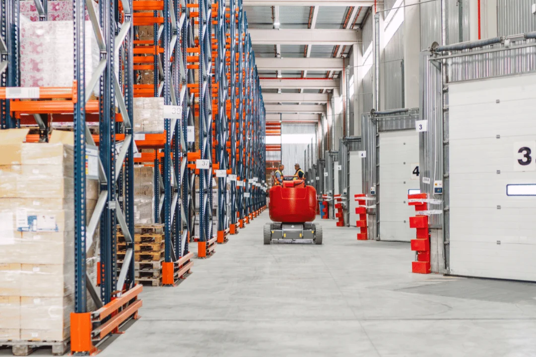 two-workers-in-a-warehouse-talking-as-a-red-automated-robot-approaches
