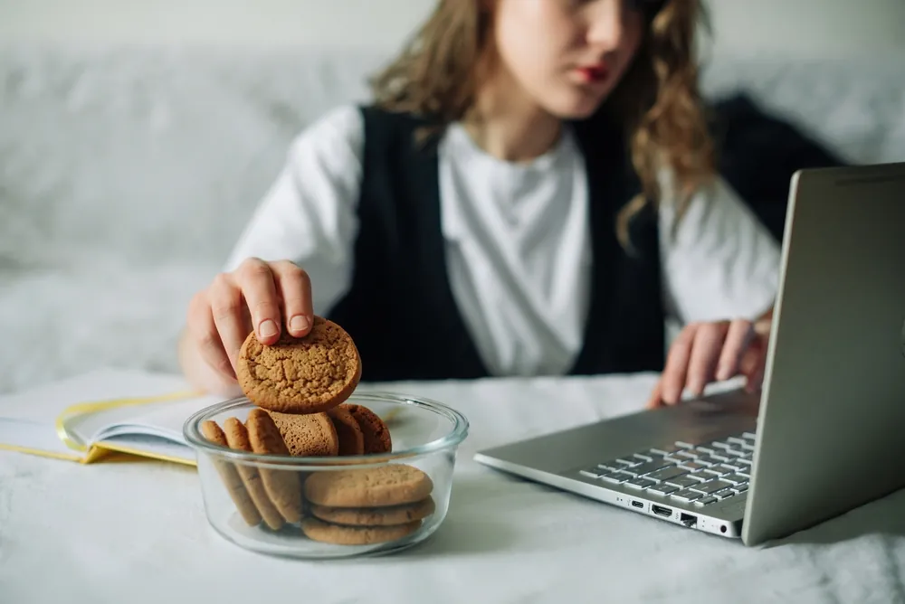 lady grabs cookie in front of laptop