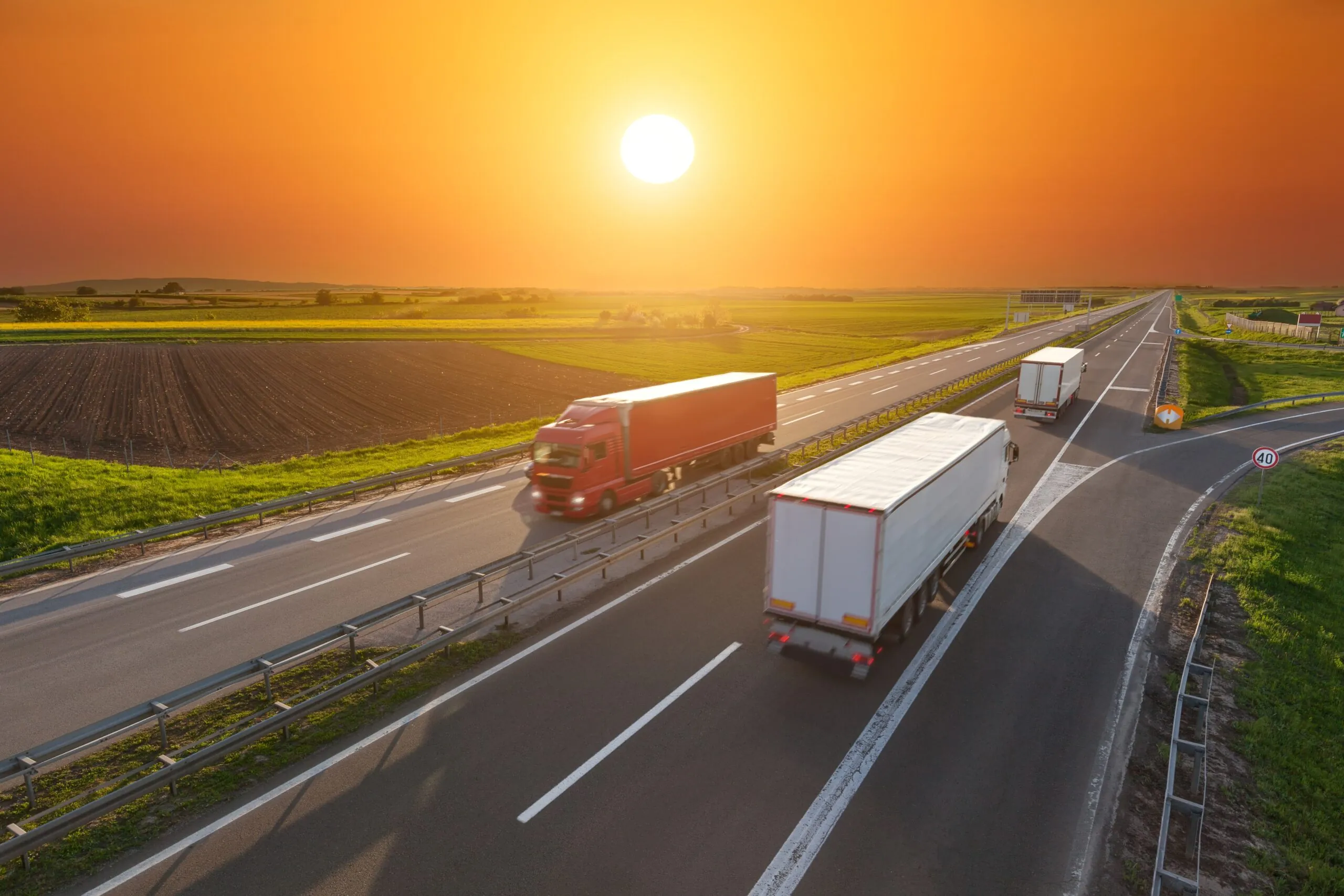 Are Your Shipments Ready for Peak Season trucks passing each other on the highway during sunset