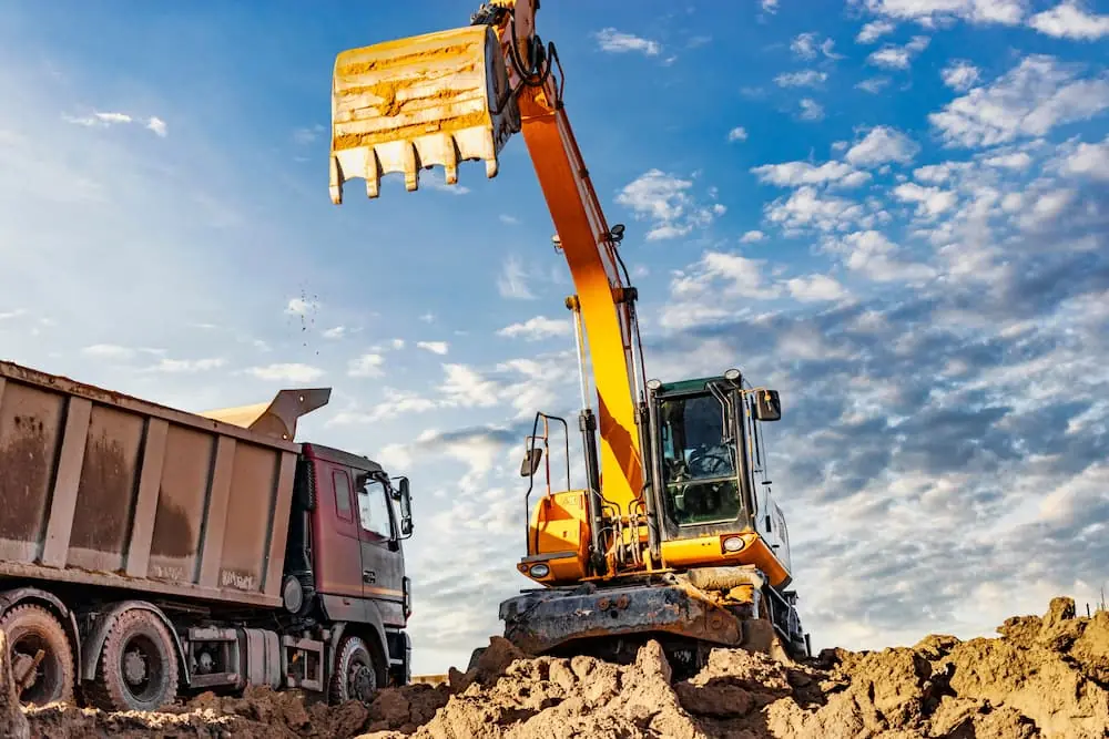 Construction Deadlines an excavator dropping dirt into a dump truck