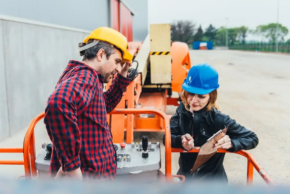 Construction Deadlines two construction workers discussing details of project on a clipboard
