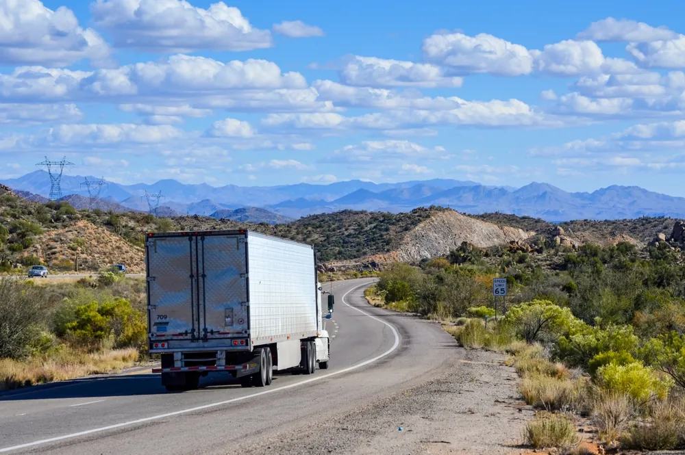 The Crackdown on CDLs and Why It Matters semi trailer truck driving down highway in the desert