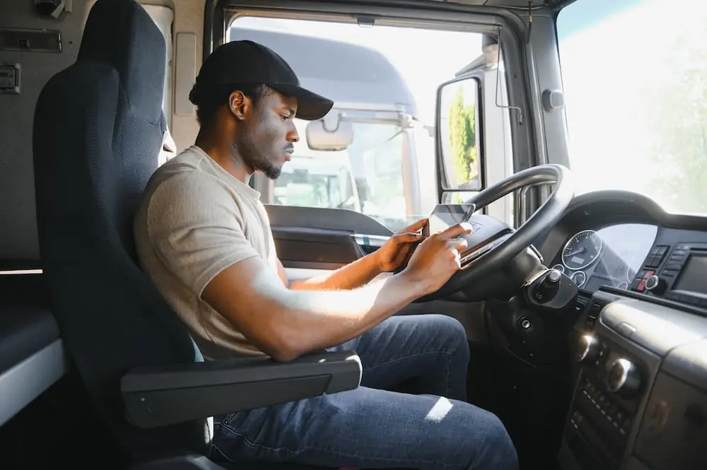 Truck Driver Mentorship male driver setting up directions on his tablet as he prepares to drive truck