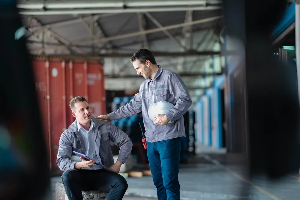 Truck Driver Mentorship one truck driver supporting another while both are on break in warehouse loading dock