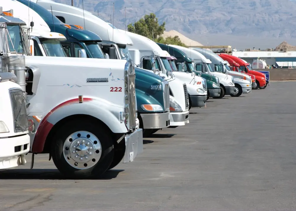 The Rise and Fight Against Chameleon Carriers row of semi trailer trucks parked in terminal parking lot