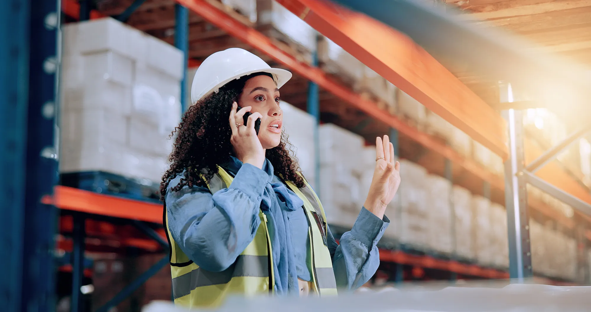 female warehouse worker on the phone holding her hand up