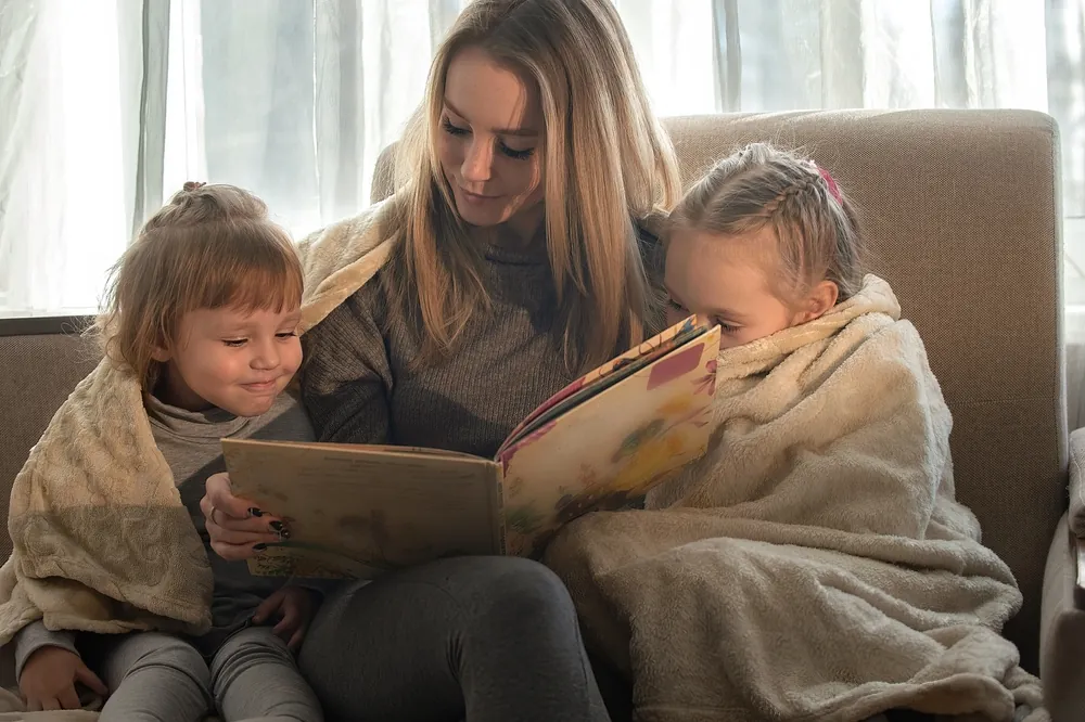 mom and kids bundled up reading a book