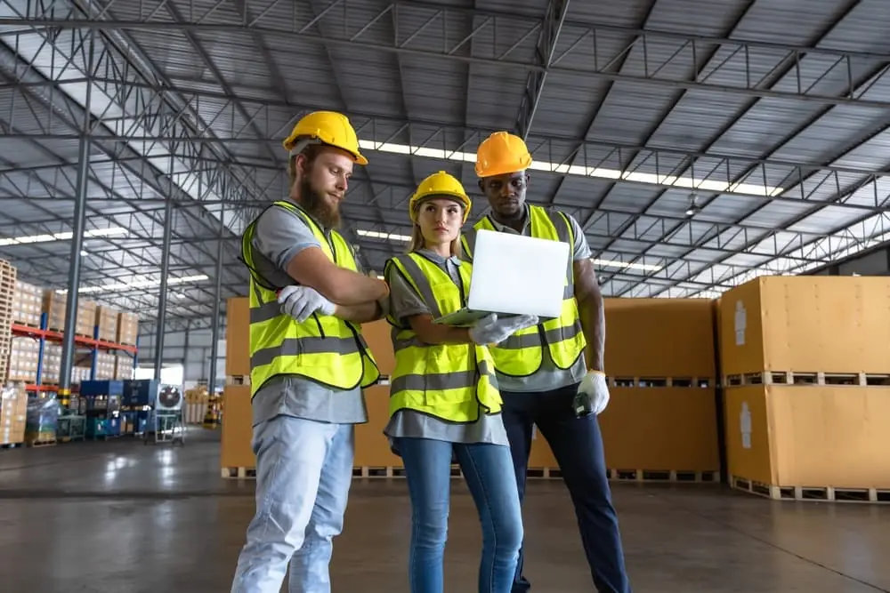 Distribution Centers vs Warehouses group of warehouse workers looking over data on laptop