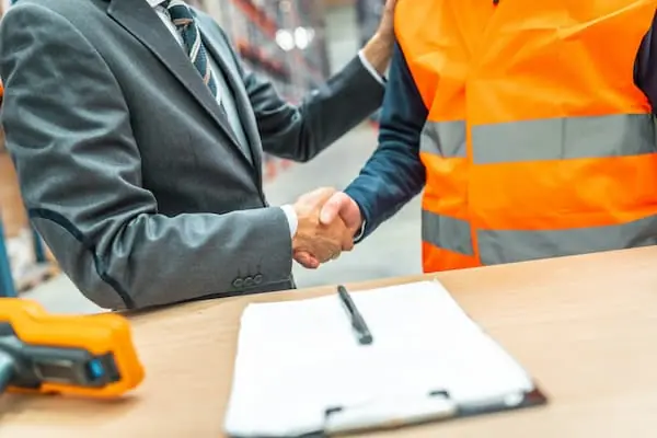 Seasonal Hiring Models a businessman and a warehouse worker shaking hands after making deal