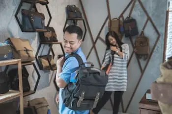 Try Before You Buy couple trying out backpacks and purses at a store