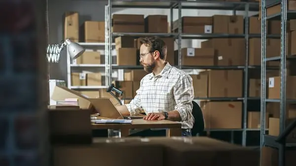 Try Before You Buy warehouse worker looking at computer in a darkened warehouse aisle