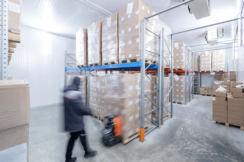 worker moving pallet in cold storage