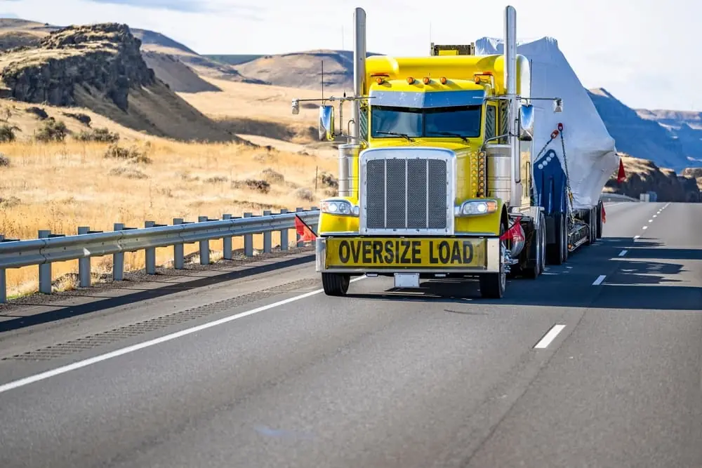 Clean Energy Logistics yellow heavy haul truck driving down desert highway